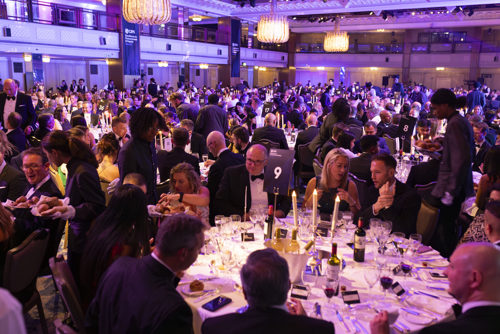 Groups of people sat around tables with candles, wine and glasses