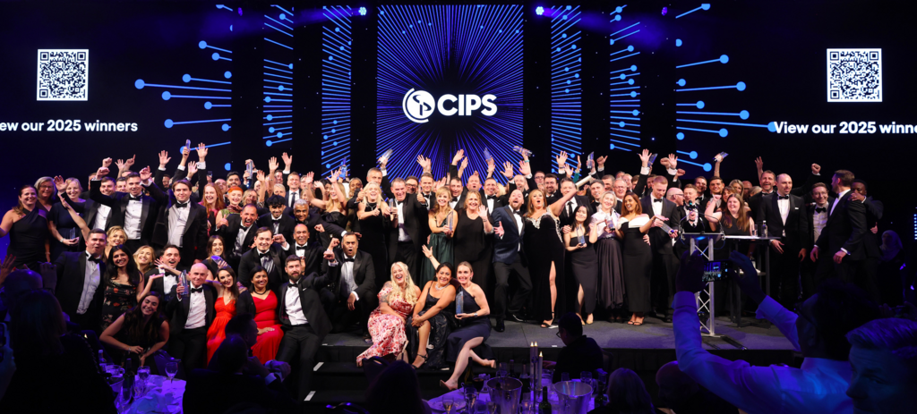 Group of 40+ people are all posing with their awards, sitting or standing on a big stage with the CIPS logo above them.