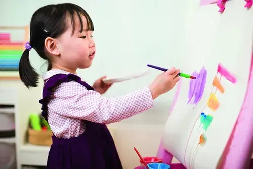 Child painting with a brush at an easel