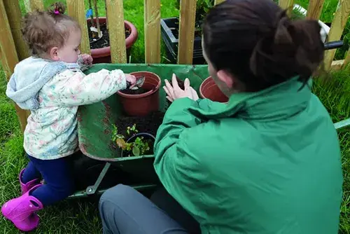 Early years child and practitioner exploring outdoor learning