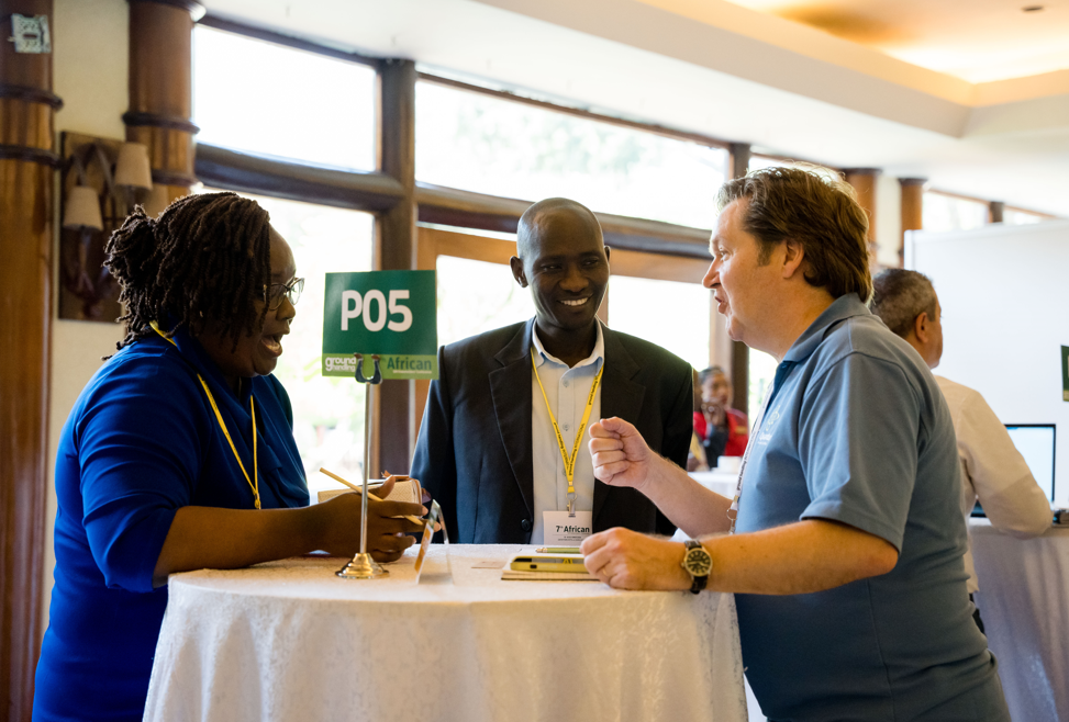 Three attendees engaged in discussion at a networking event table