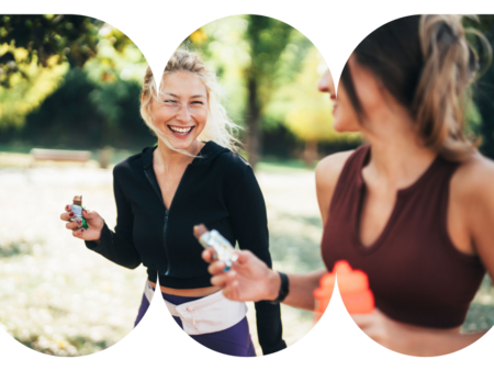 Two people running side by side in a sunny park, holding water bottles and energy snacks.